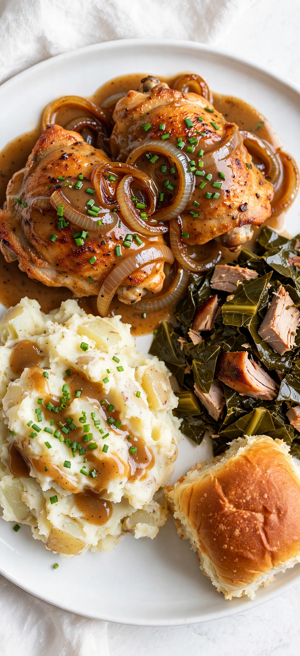 Smothered chicken with chunky mashed potatoes, collard greens and a dinner roll